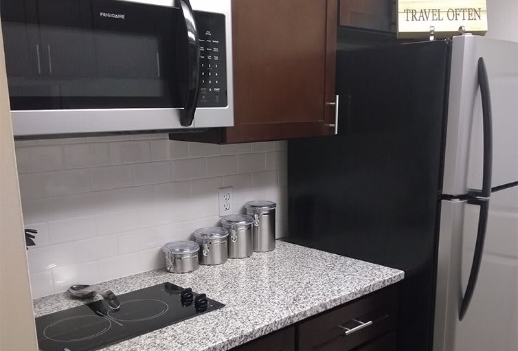 Modern kitchen with a microwave, storage jars, and sleek countertop.