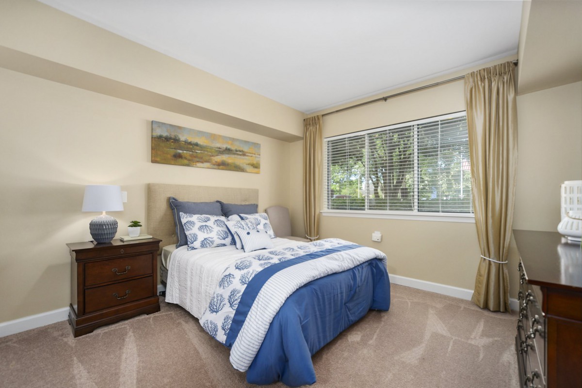 A cozy bedroom with a neatly made bed and large window.