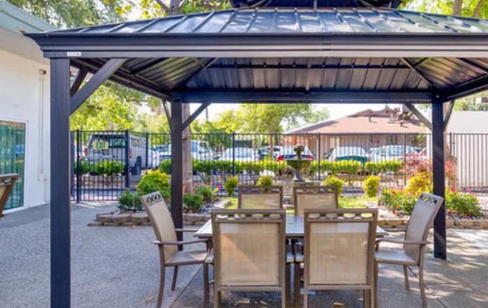 Outdoor patio with a gazebo and dining furniture set in a garden setting.