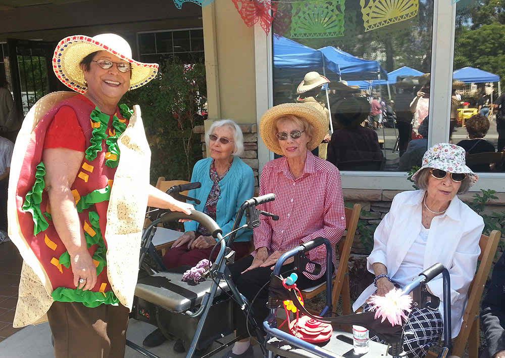 A group of elderly women wearing hats enjoying a sunny day outdoors.