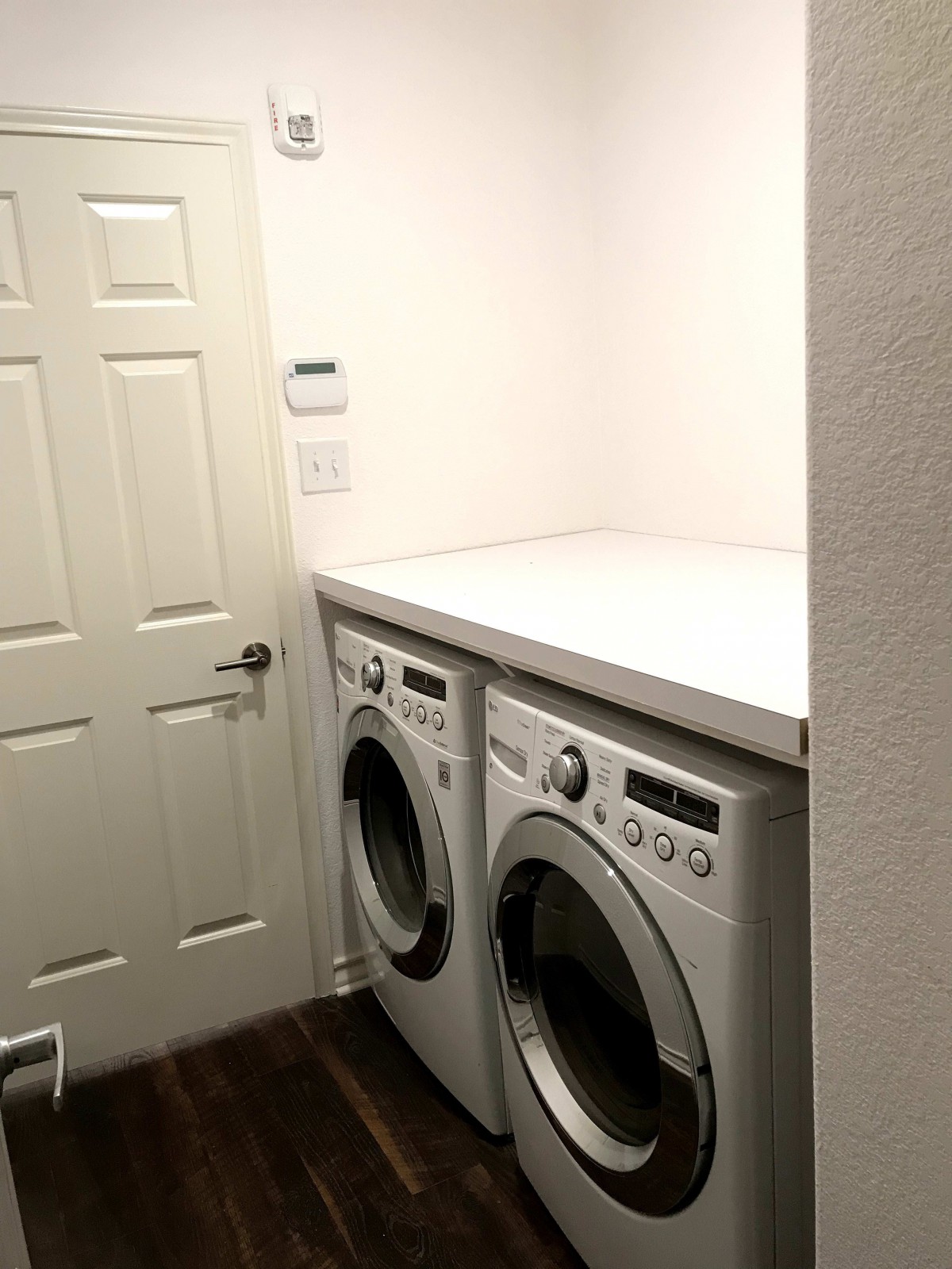 A neatly organized laundry room with a washer and dryer beneath a countertop.