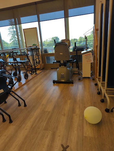 A room equipped with exercise machines and walking aids for rehabilitation.