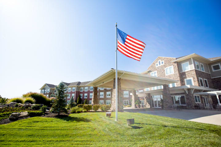 A sunny day with an American flag waving in front of a large building.
