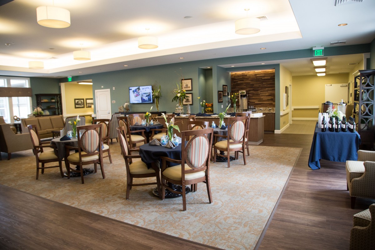 A well-lit dining area with multiple round tables and cushioned chairs, featuring elegant decor.
