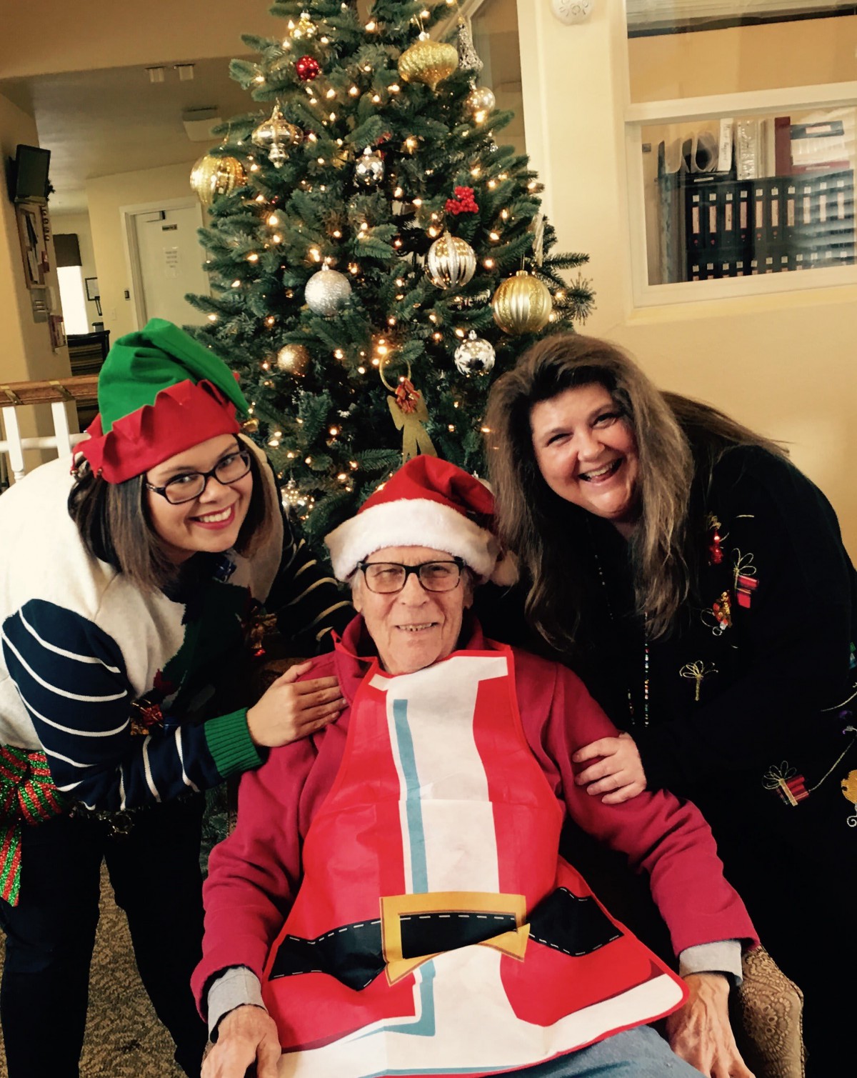 A cheerful family gathering in front of a Christmas tree, with one member dressed as Santa Claus.