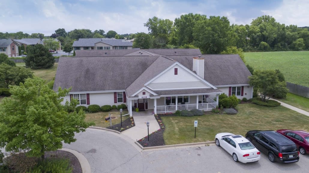 Aerial view of a residential building with a driveway and parking area in a suburban setting.