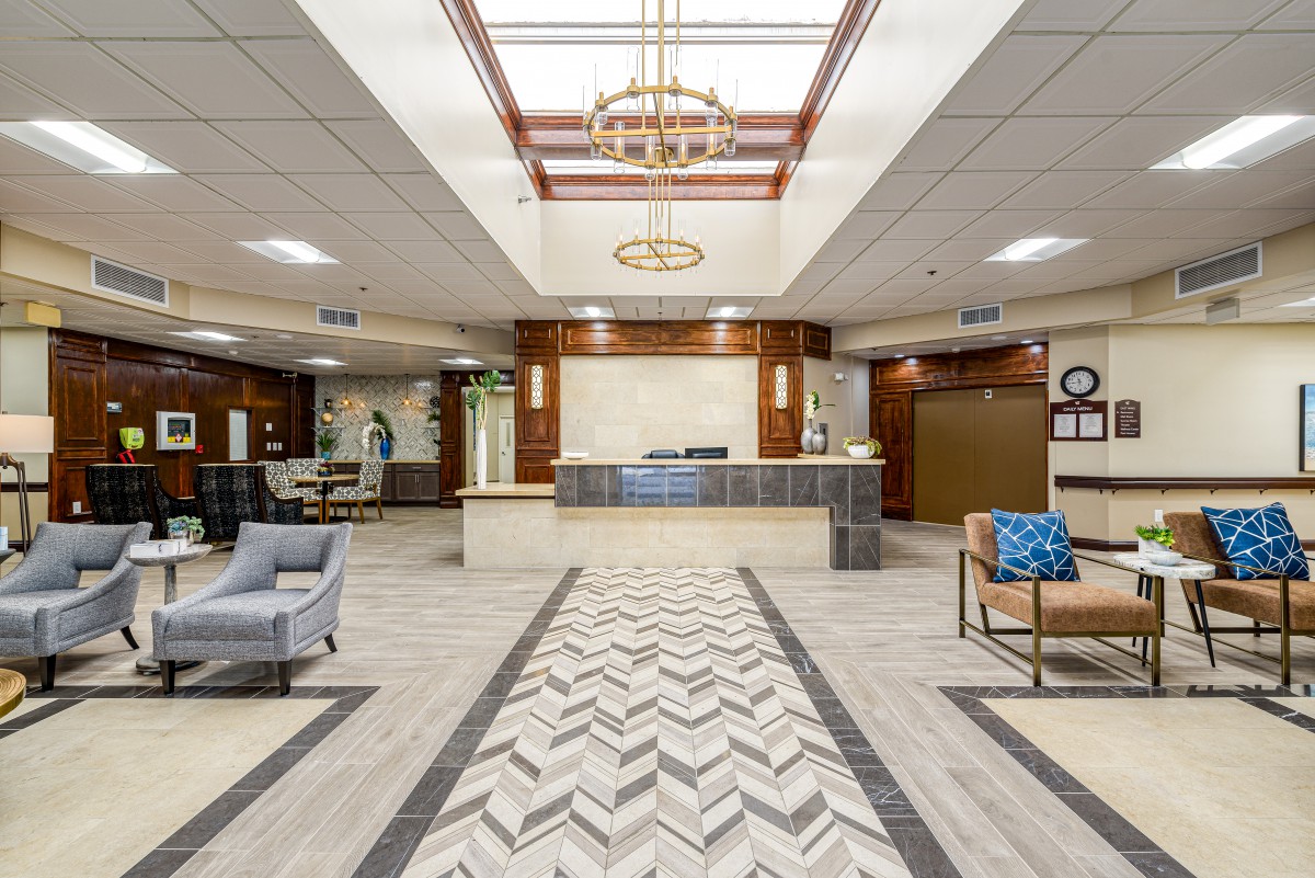 A modern lobby with a reception desk, stylish seating, and a decorative chandelier.