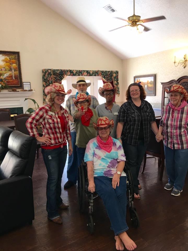 A group of people wearing cowboy hats and plaid shirts gathered indoors.