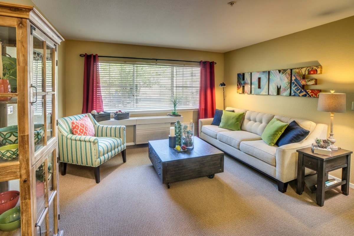 A cozy living room with a sofa, armchair, and coffee table, decorated in warm tones.
