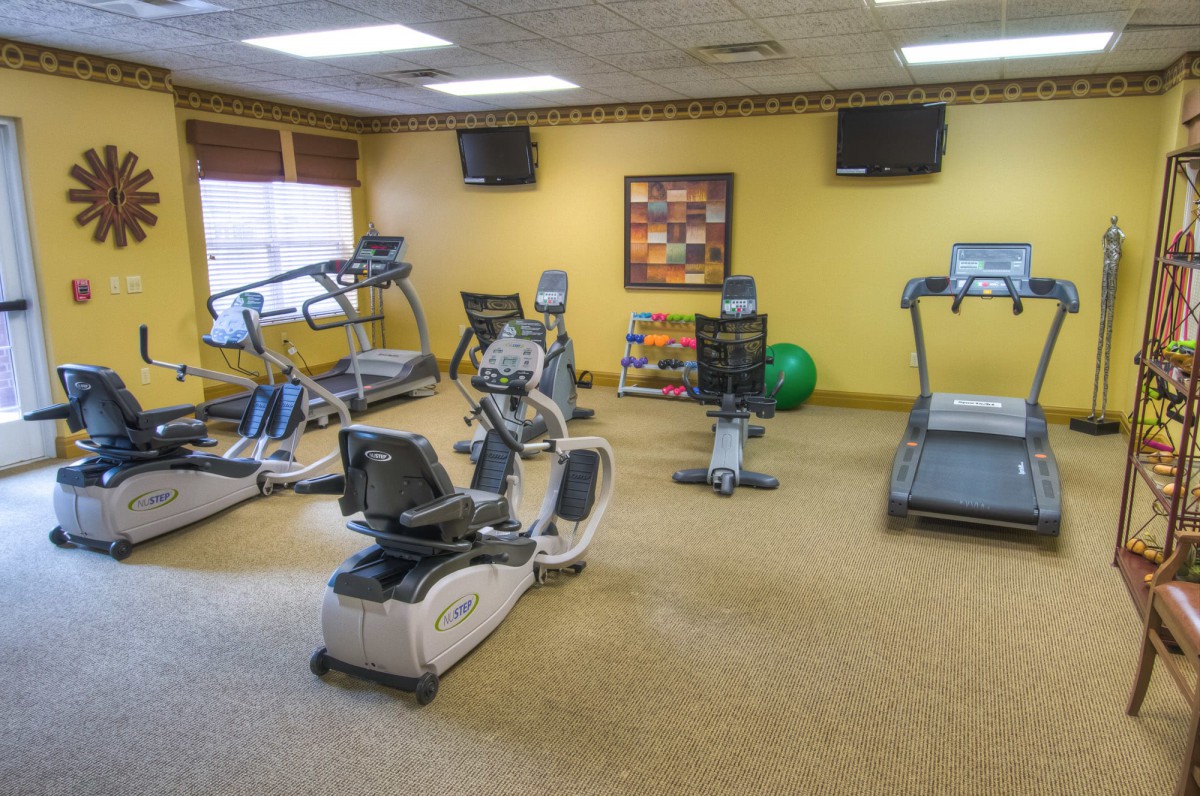 An indoor gym equipped with various exercise machines including a treadmill, stationary bike, and elliptical trainer.