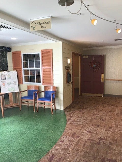 A small waiting area with chairs and a sign in a corridor.