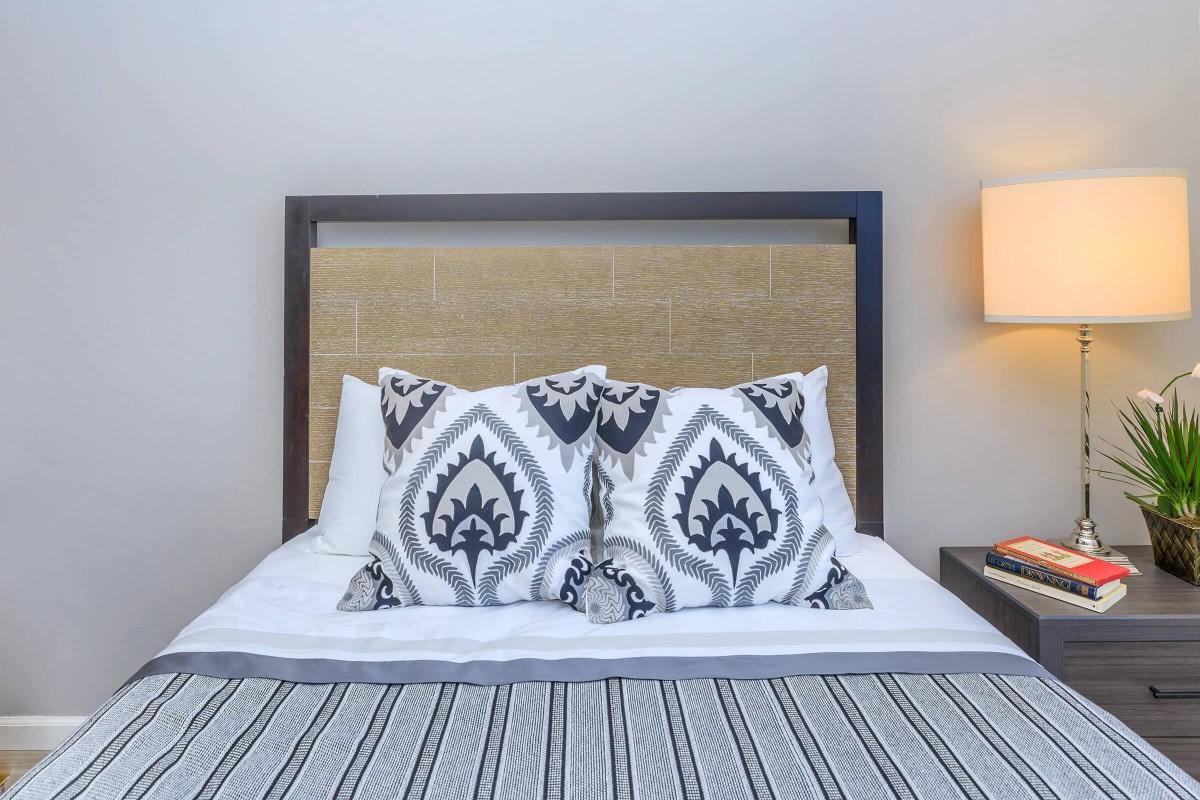 A neatly made bed with patterned pillows and a bedside lamp in a modern bedroom.