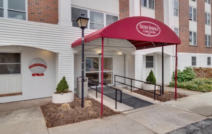 Front entrance of a building with a red awning and accessibility ramp.