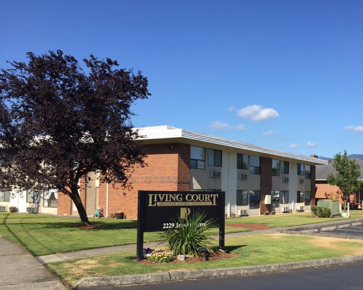 An exterior view of an apartment building with a sign labeled 'Living Court'.