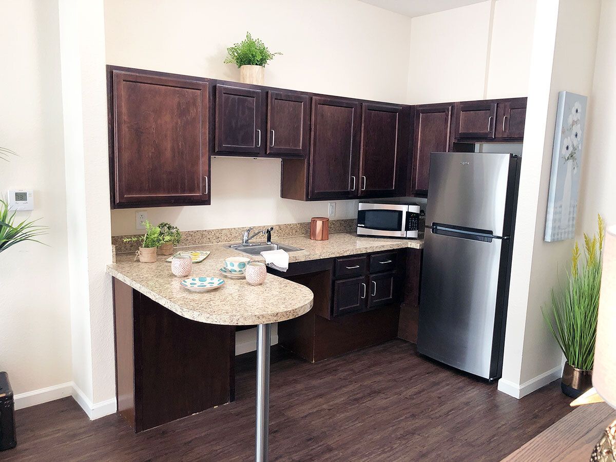 A modern kitchen with dark cabinets and stainless steel appliances.