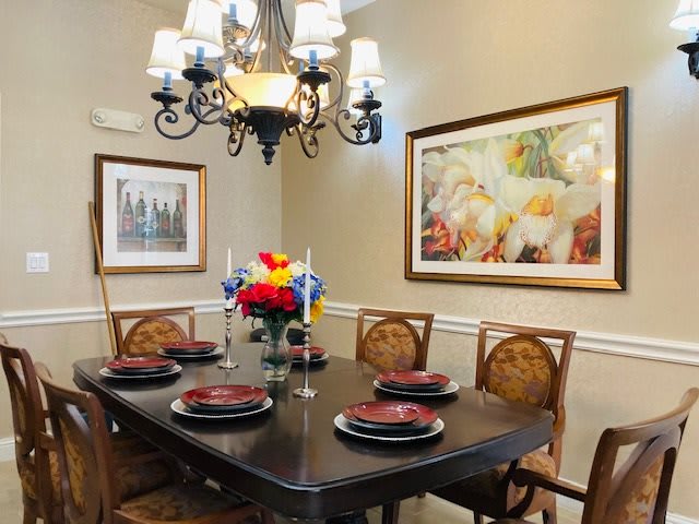 A beautifully set dining room table with elegant decor and a chandelier overhead.
