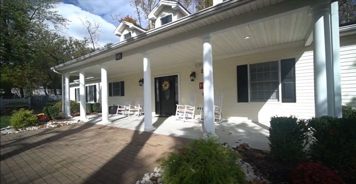A welcoming porch with white columns and rocking chairs in front of a house.