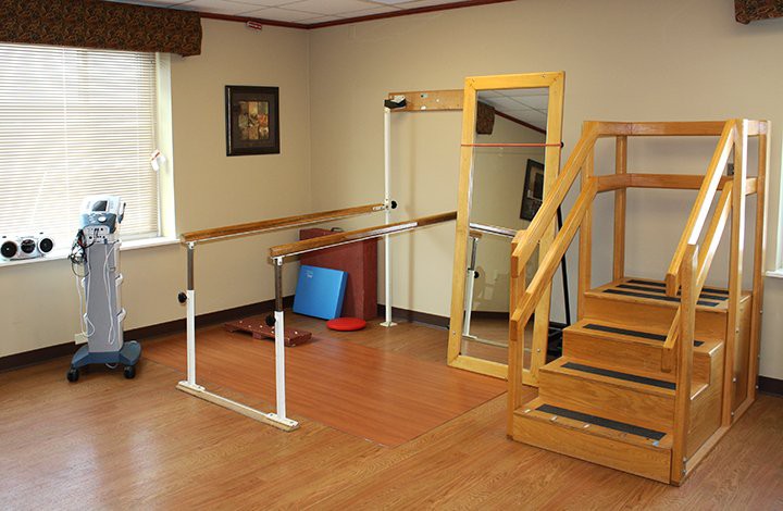 A rehabilitation therapy room with balance bars, a mirror, and stairs for physical exercises.