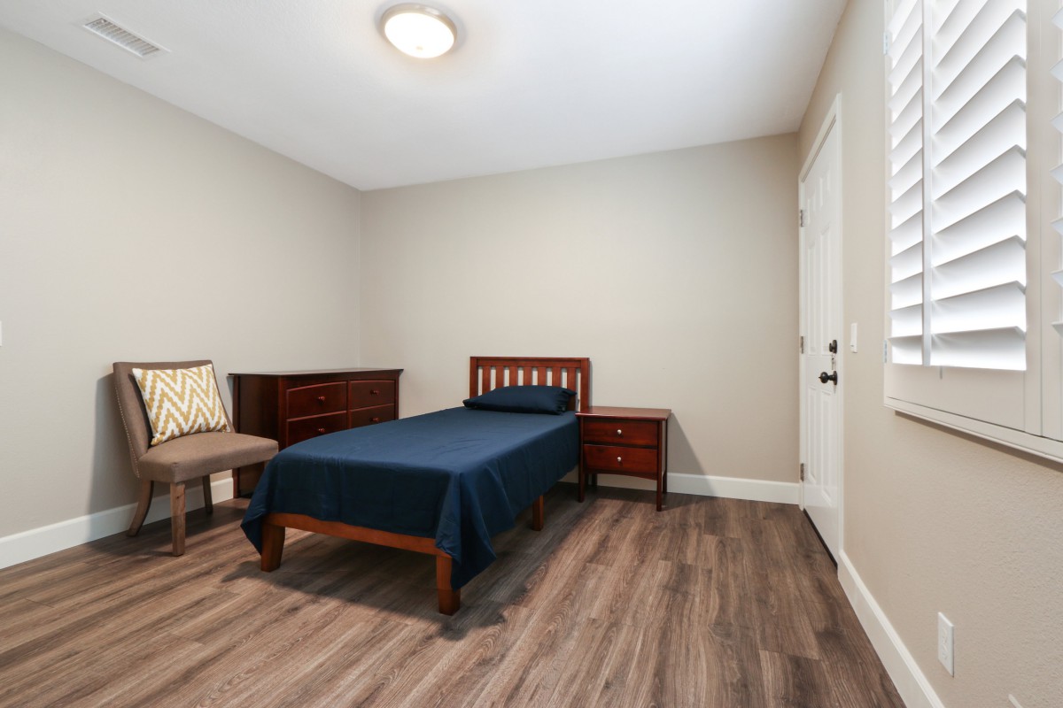 A minimalist bedroom with a single bed and wooden flooring.