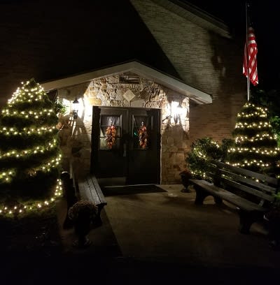 A cozy entrance adorned with Christmas lights and wreaths at night.