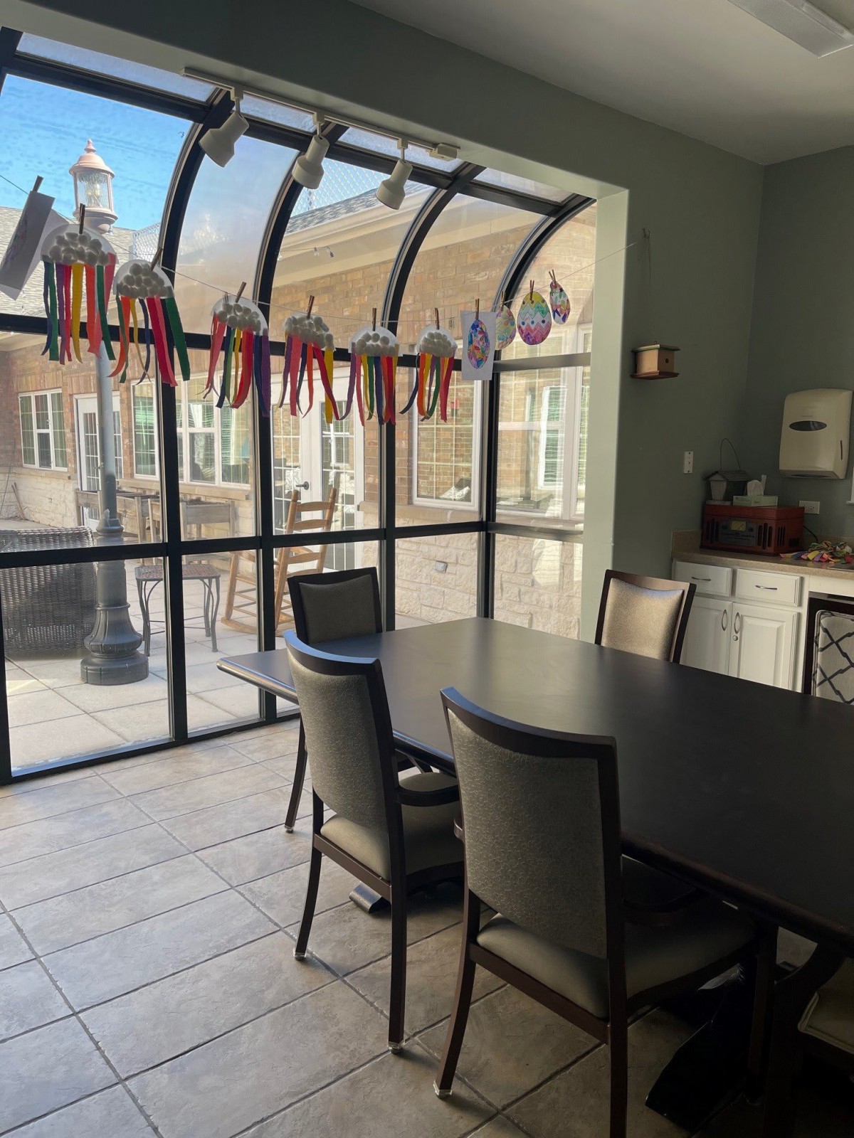 A modern dining area with large glass windows, featuring a table and chairs.