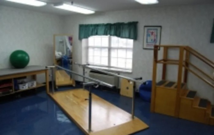 A rehabilitation room equipped with parallel bars and other exercise equipment.