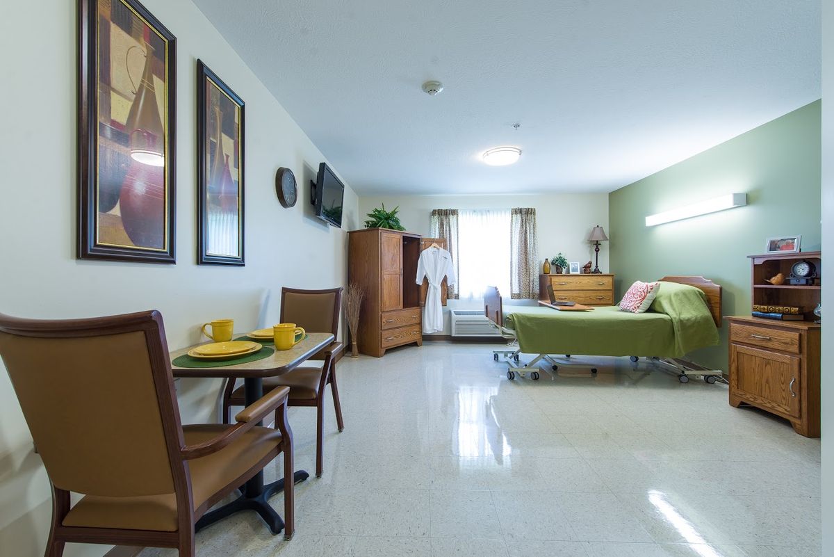 A well-lit room with a bed, table, chairs, and wall decorations.