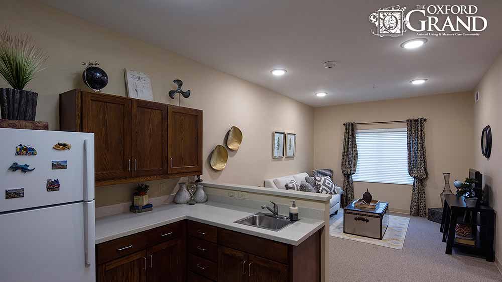 An open-concept kitchen with dark wood cabinets and a view into a cozy living room area.