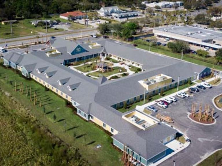 Aerial view of a large building with a central courtyard and surrounding parking area.