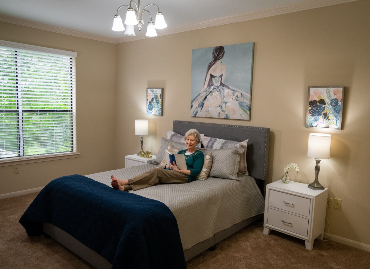 A cozy bedroom with a person reading on the bed, surrounded by elegant decor and artwork.