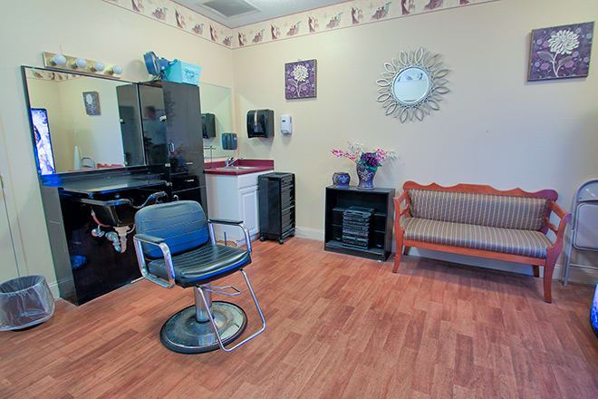 Interior of a hair salon featuring a barber chair, mirror, and waiting area.