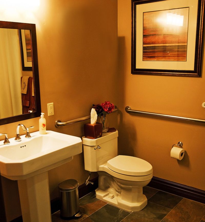 A well-decorated bathroom featuring a pedestal sink, toilet, and framed artwork on the wall.