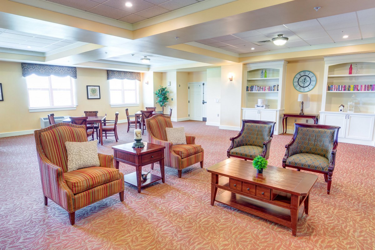 A cozy living room with comfortable chairs and sofas, featuring a warm color palette and decorative elements.