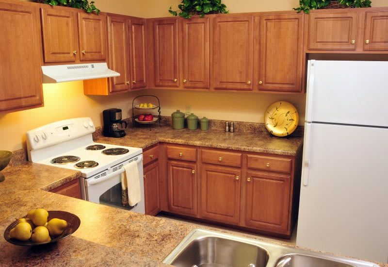 A cozy kitchen with wooden cabinets, a stove, refrigerator, and countertop.