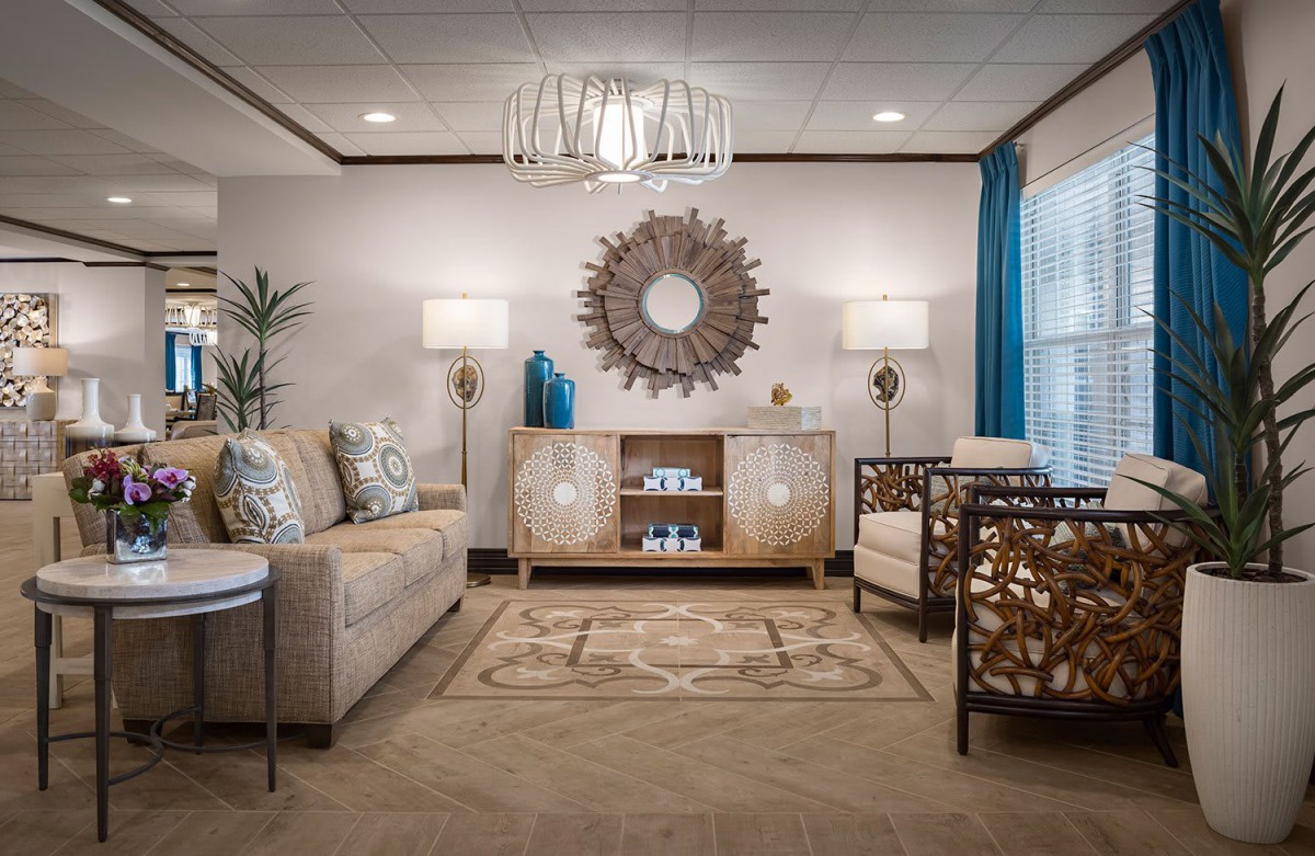 A modern living room with stylish furniture and decor, featuring a large mirror and ambient lighting.