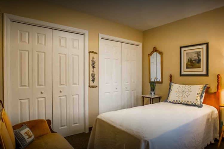 A cozy bedroom with a neatly made bed, double closets, and simple decor.