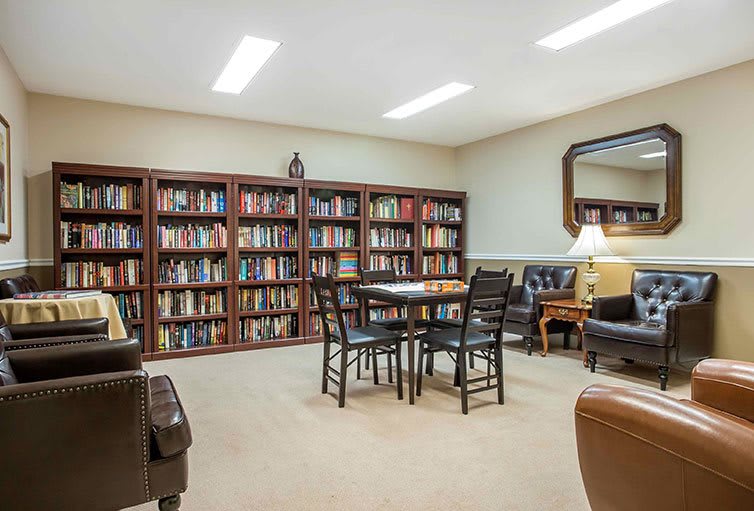 A cozy library reading room with bookshelves, a table, and comfortable seating.