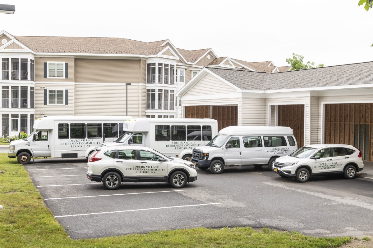 A parking lot with several shuttle vehicles parked in front of a building.