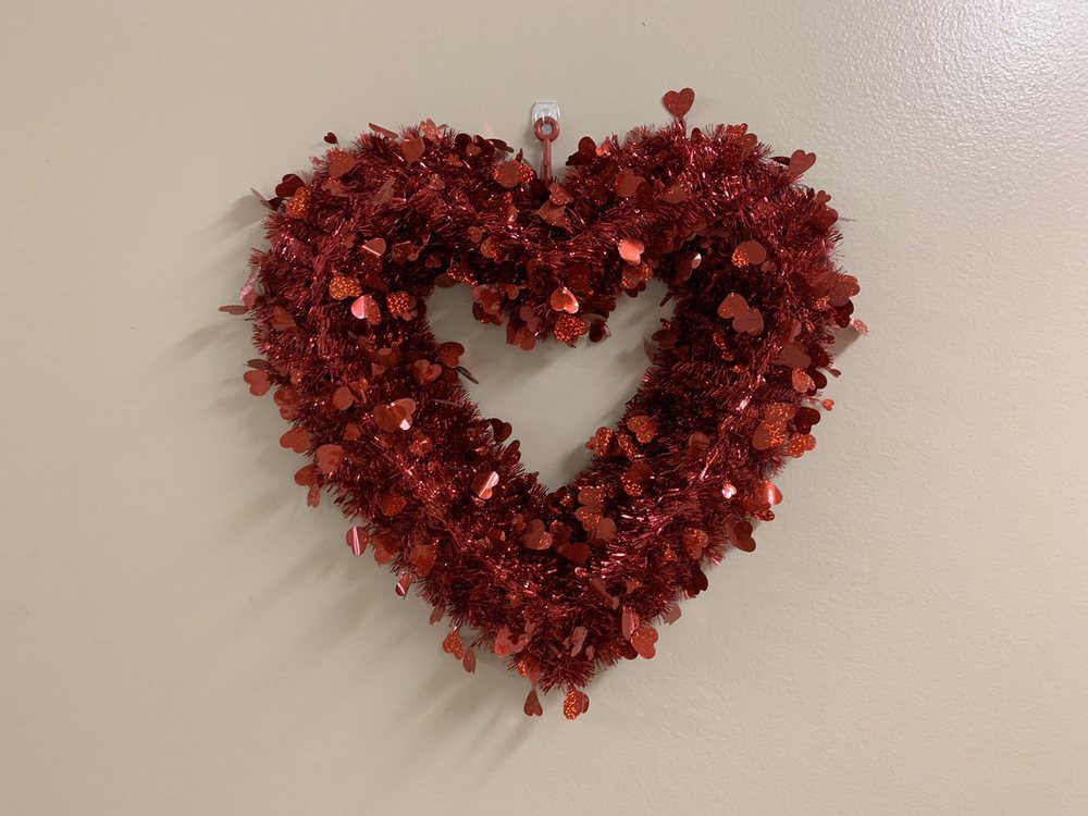 A red heart-shaped wreath decoration hanging on a wall.