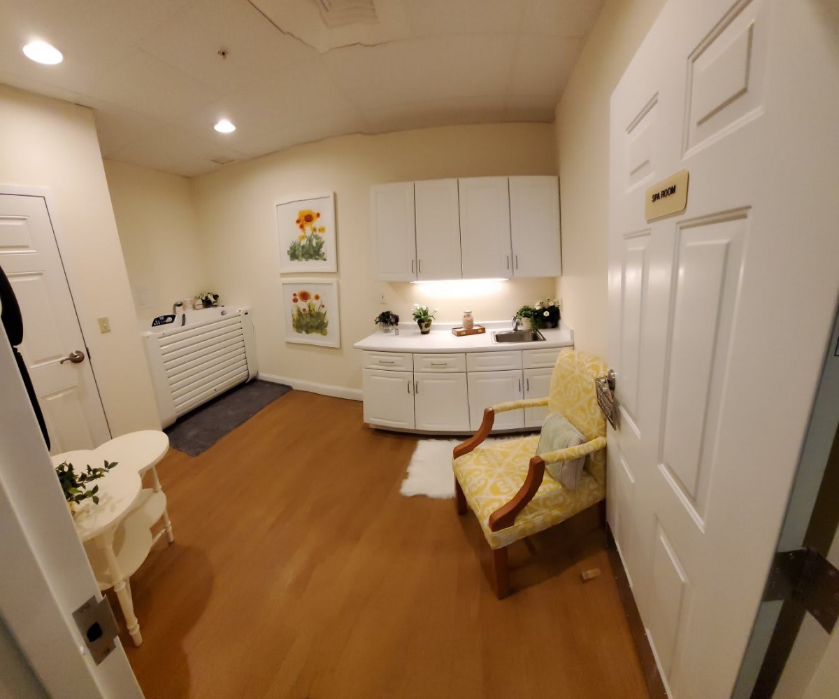 A cozy room with a chair, table, cabinets, and decorative artwork.