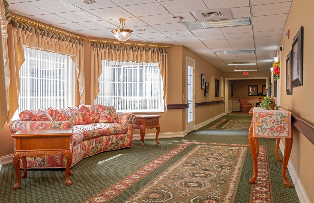 A warmly decorated hallway with a floral sofa and patterned carpet.