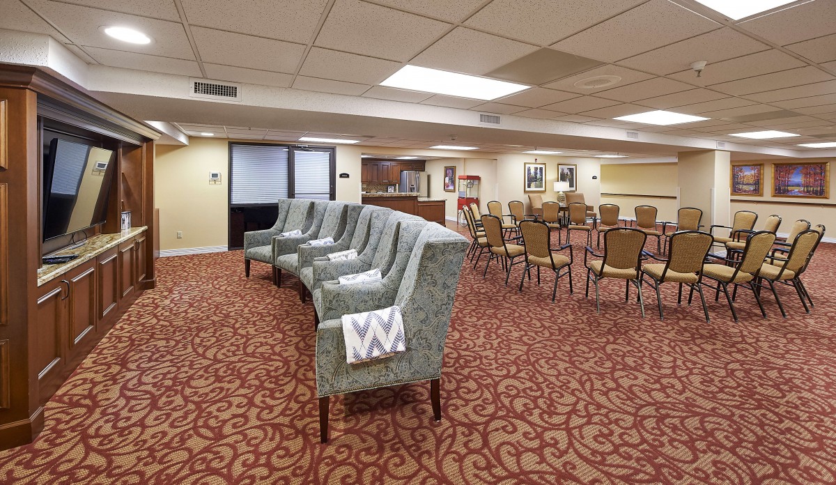 A spacious meeting room with patterned chairs and carpeted flooring.