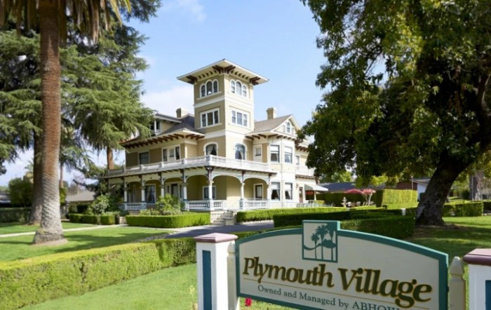 Historic Victorian-style building with lush gardens and a sign reading 'Plymouth Villa'.