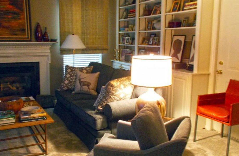 A cozy living room with a sofa, lamp, and bookshelves filled with decor items.