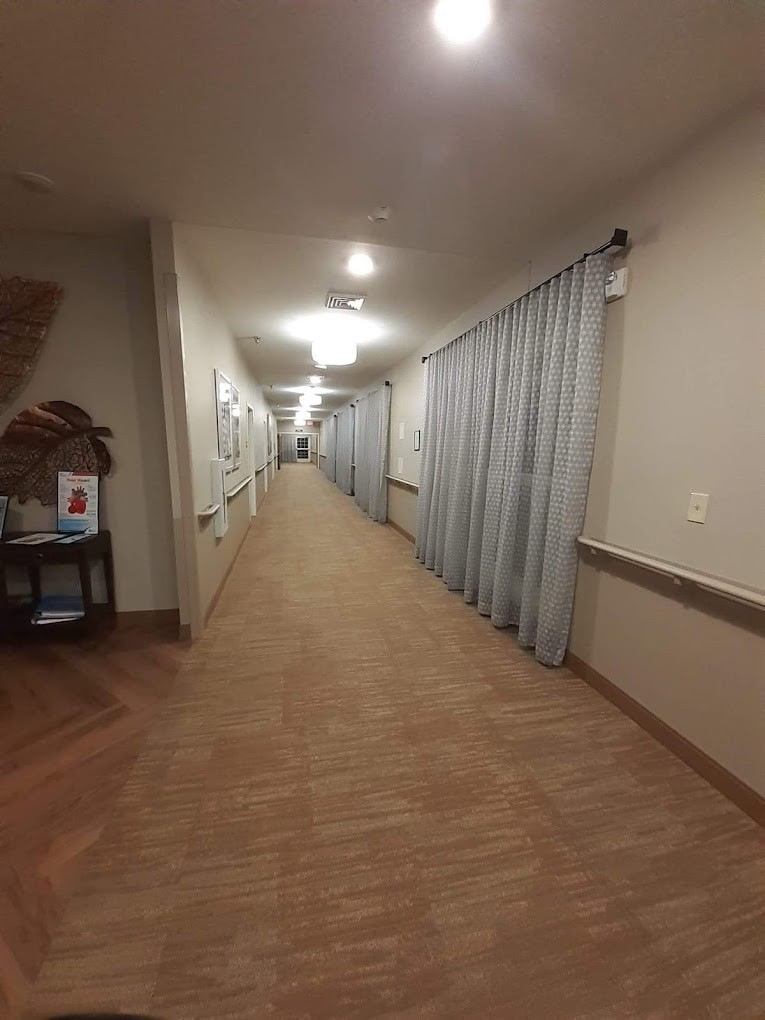 A long hallway with curtains on one side and ceiling lights illuminating the corridor.