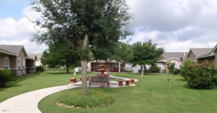 A landscaped garden area featuring a central fountain, surrounded by benches and trees.