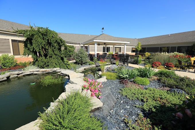 A beautifully landscaped garden with a pond and pathway leading to a building under a clear blue sky.