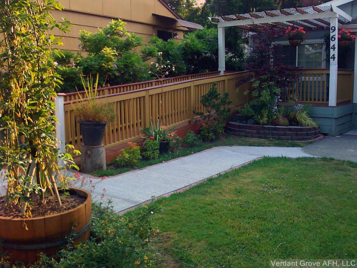 A well-maintained backyard garden with a lawn, plants, and a wooden pergola.
