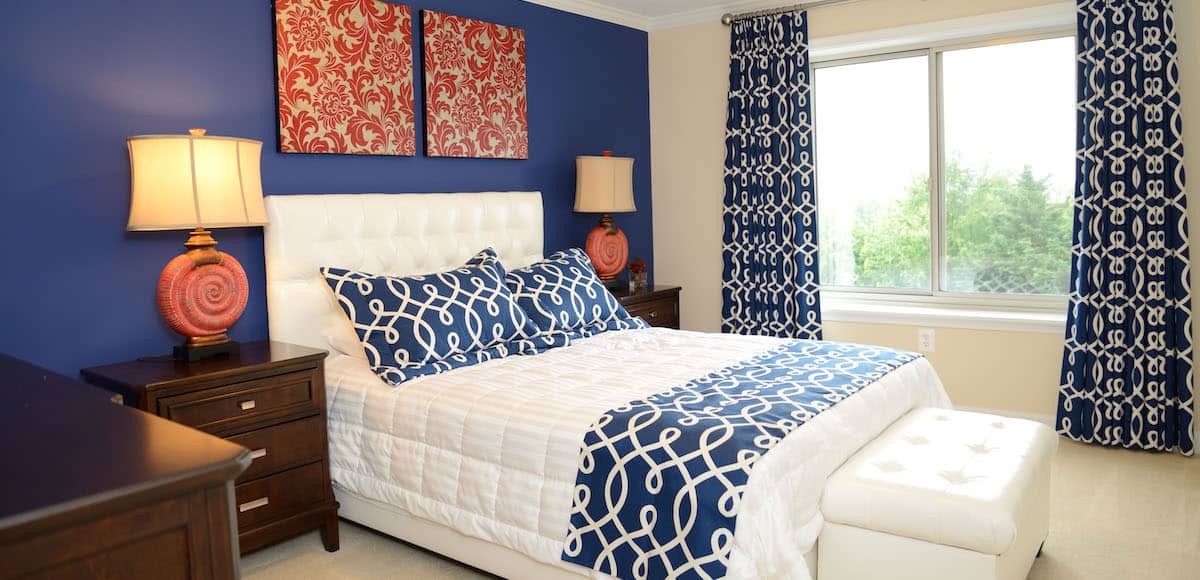 A modern bedroom with blue and white patterned decor and vibrant wall art.