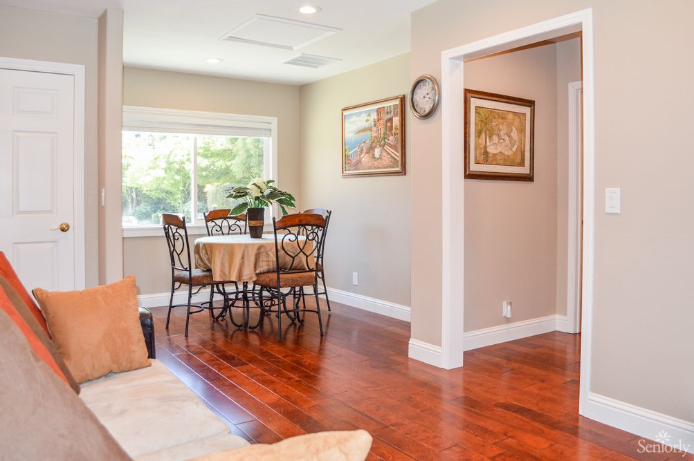 A cozy dining area with a round table, surrounded by chairs and illuminated by natural light from the window.